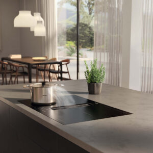 Miele Induktionskochfeld mit integriertem Dunstabzug auf Kücheninsel, Topf mit aufsteigendem Dampf in heller, offener Wohnküche bei A2 Küchen