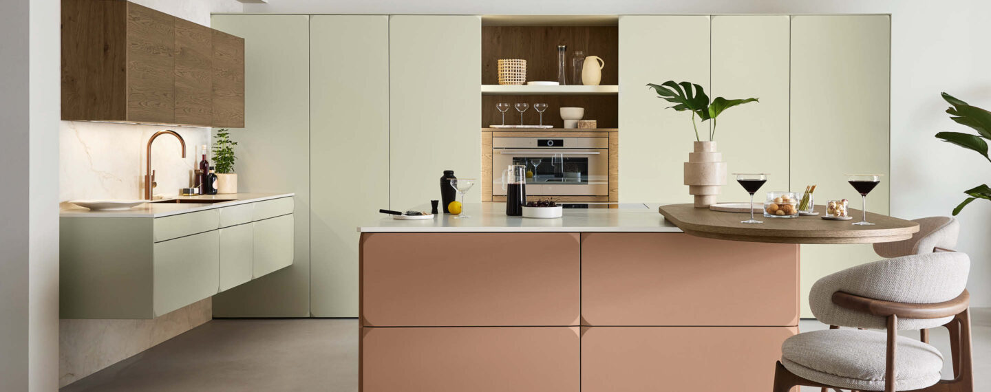 Moderne Ballerina Küche in Pastellgrün und Terrakotta mit Kücheninsel und Holzdetails, integrierte Beleuchtung und Geräte, stilvoll für Kochen und Wohnen